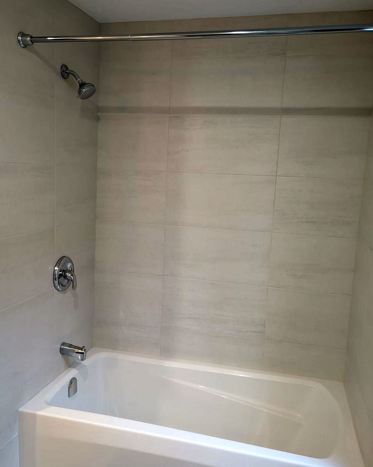 Alcove bathtub with a tiled surround, a single-handle shower valve, a showerhead and a tub spout